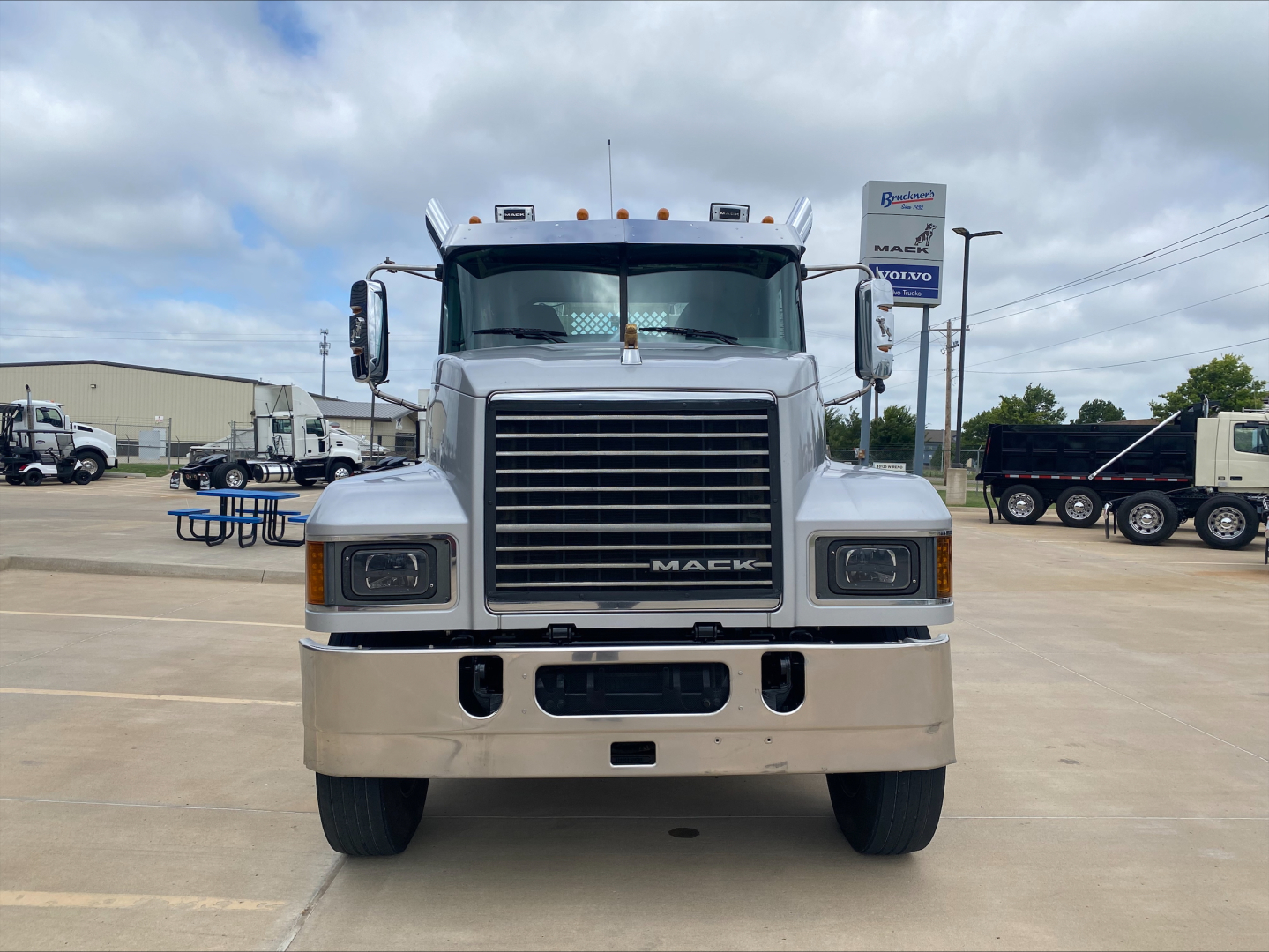 Mack PI64T conventional daycab truck front view showing large chrome grille, Mack emblem, dual headlights, light bar on roof, and bumper.