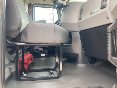 Truck cab interior showing driver's seat and dashboard in a 2019 Mack PI64T with visible floor area and seat mount.