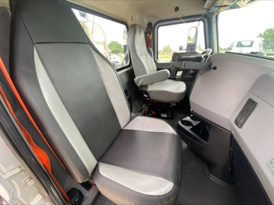 Truck cab interior of a 2019 Mack PI64T showing front bench and passenger seat with black and gray upholstery, dashboard, steering wheel, and center console.