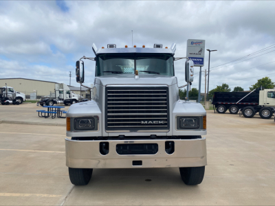 Mack PI64T conventional daycab truck front view showing large chrome grille, Mack emblem, dual headlights, light bar on roof, and bumper.