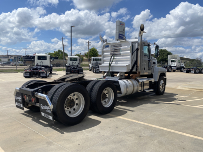 Mack PI64T heavy-duty semi truck rear view showing dual rear axles and fifth wheel, chrome fuel tanks, vertical exhaust, and daytime sky.
