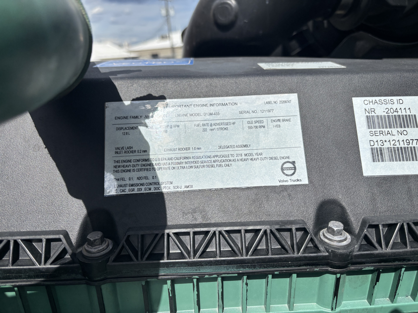 Label on Volvo VNL engine bay with Vehicle Identification Number and serial sticker text; visible text includes chassis ID NR - 204111, serial no D13T211... and a white label with multiple lines of small print.