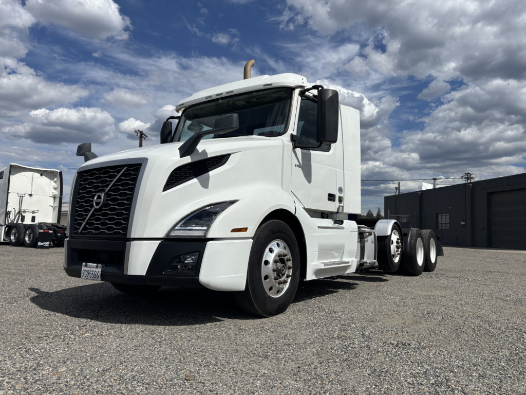 Volvo VNL84T300 daycab tractor in white, side view showing front grille, cab, and tandem rear axles.