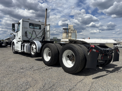 Truck chassis of a 2019 Volvo VNL84T300 daycab with triple rear axles and sleeper cab visible, showing exhaust stack and fuel lines.