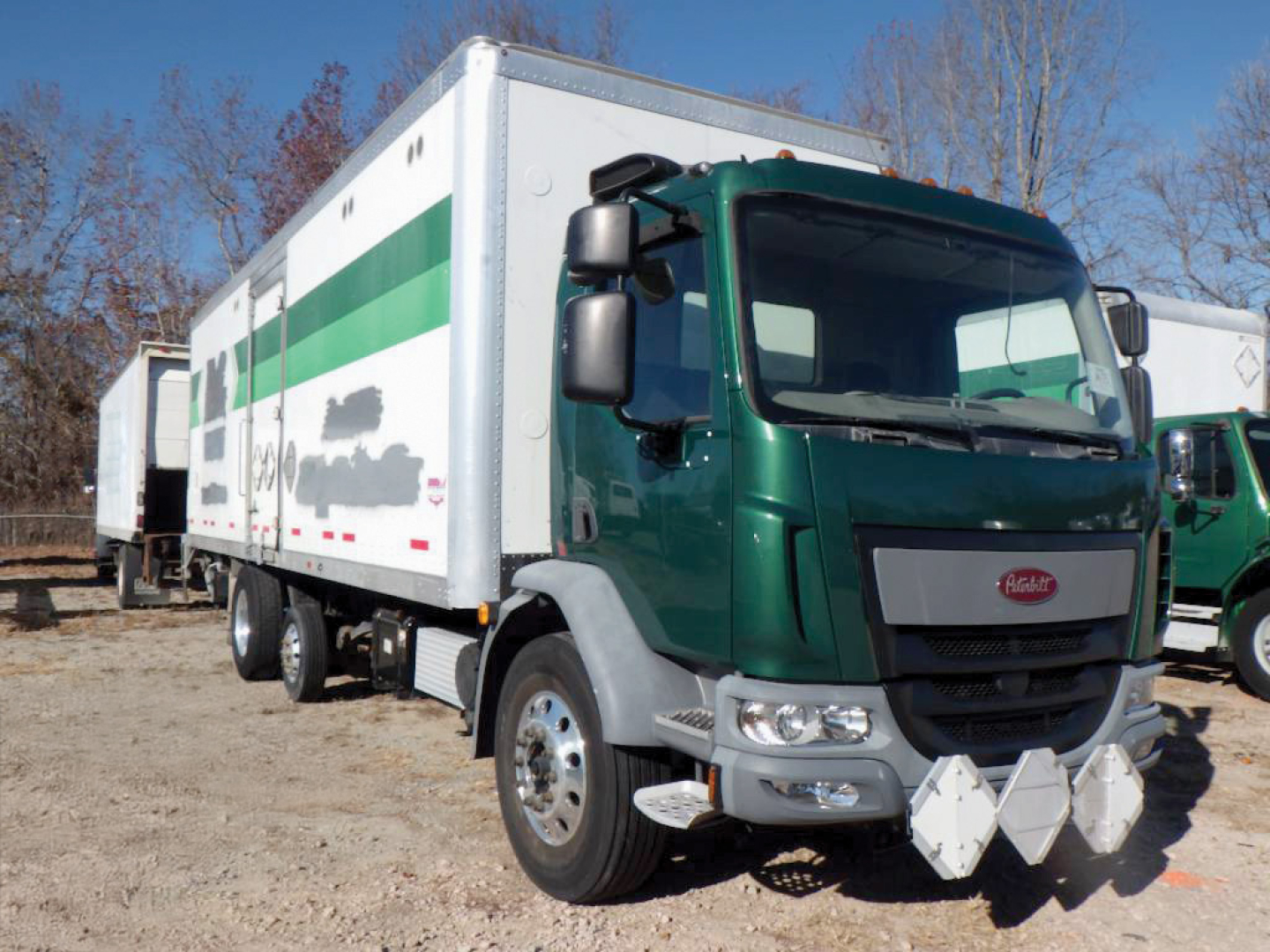 Peterbilt 220 cabover truck in green with white cargo box and diamond plate bumper