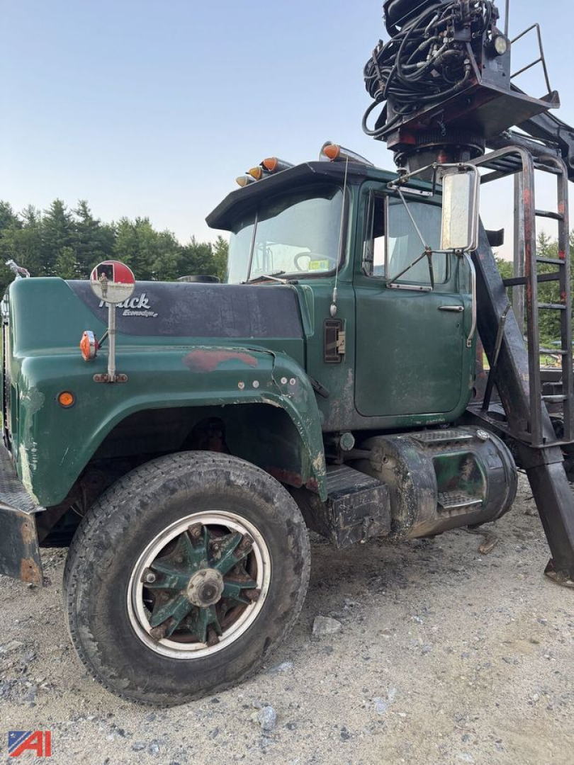 Mack R686ST log trucking truck in green with crane attachment on back, front left wheel visible, rugged tires, side mirror and weathered exterior.