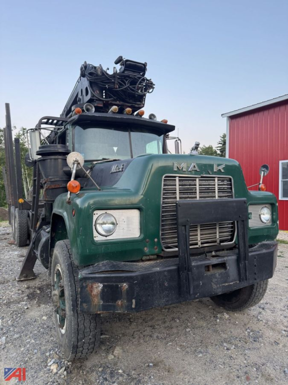 Mack R686ST log truck with front grille and crane on top, green cab, black bumper, attached logging equipment and wheel arches.