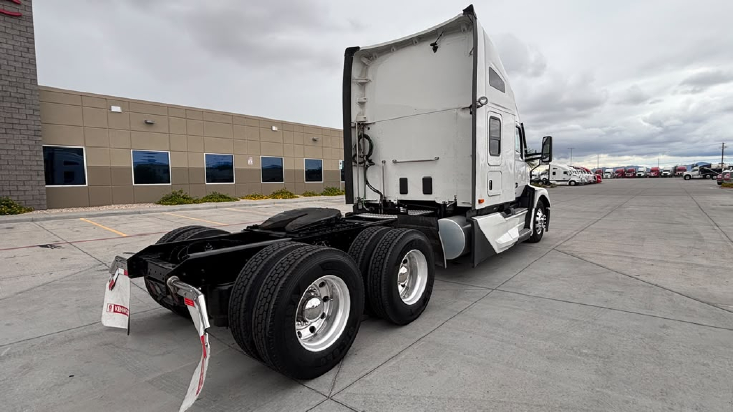 Kenworth T680 tractor rear view showing tandem axle and sleeper cab, with white exterior and chrome wheels.