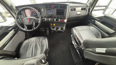 Kenworth T680 cab interior showing steering wheel, dashboard, center console, and front seats with standard gauges and controls.
