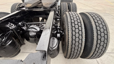 Dual rear axles of a Kenworth T680 tractor showing suspension, drive shafts, and tires with dual-tire configuration.
