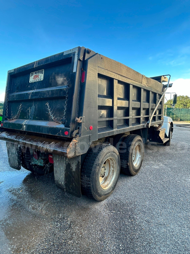 Dump truck rear and side view showing black dump bed, dual rear axles, and wheels; no legible text visible except a small sticker on the tailgate.
