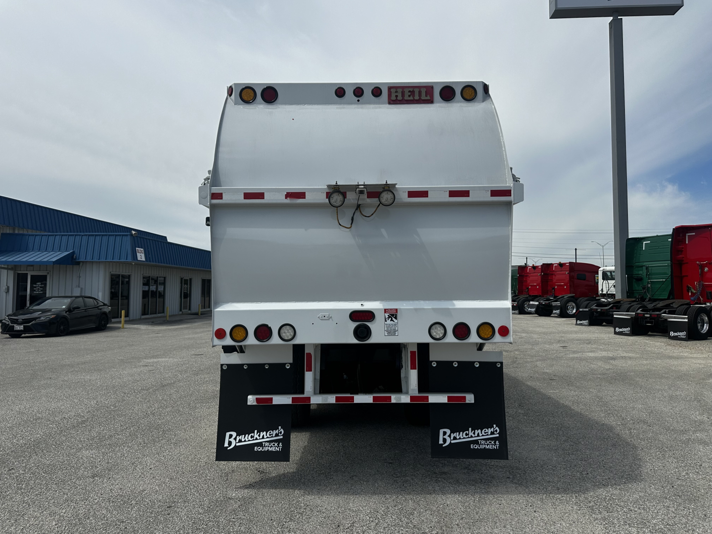 Back view of a white Autocar XPEDITOR dump truck with rear tailgate, lights, and two black mud flaps labeled Bruckner's Equipment. VIN plate not visible.