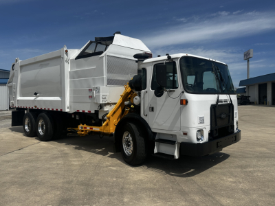 Autocar XPEDITOR waste truck in side view showing white cab, dump bed, hydraulic arm, and rear wheels.