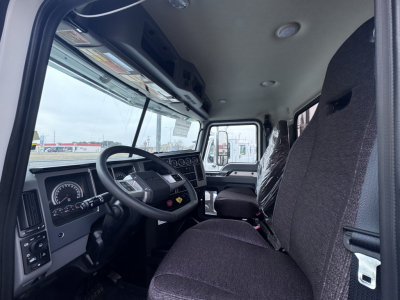Truck cab interior showing steering wheel dashboard gauges and driver seat in a new Mack PI64 dump truck.