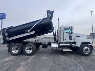 Dump truck side view showing 6x4 configuration with cargo bed raised, Mack PI64 badge visible, white cab, black dump body, dual rear wheels, chrome exhaust, stock number 70242.