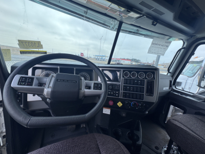 Mack PI64 truck interior showing steering wheel, dashboard with gauges, and control panel.