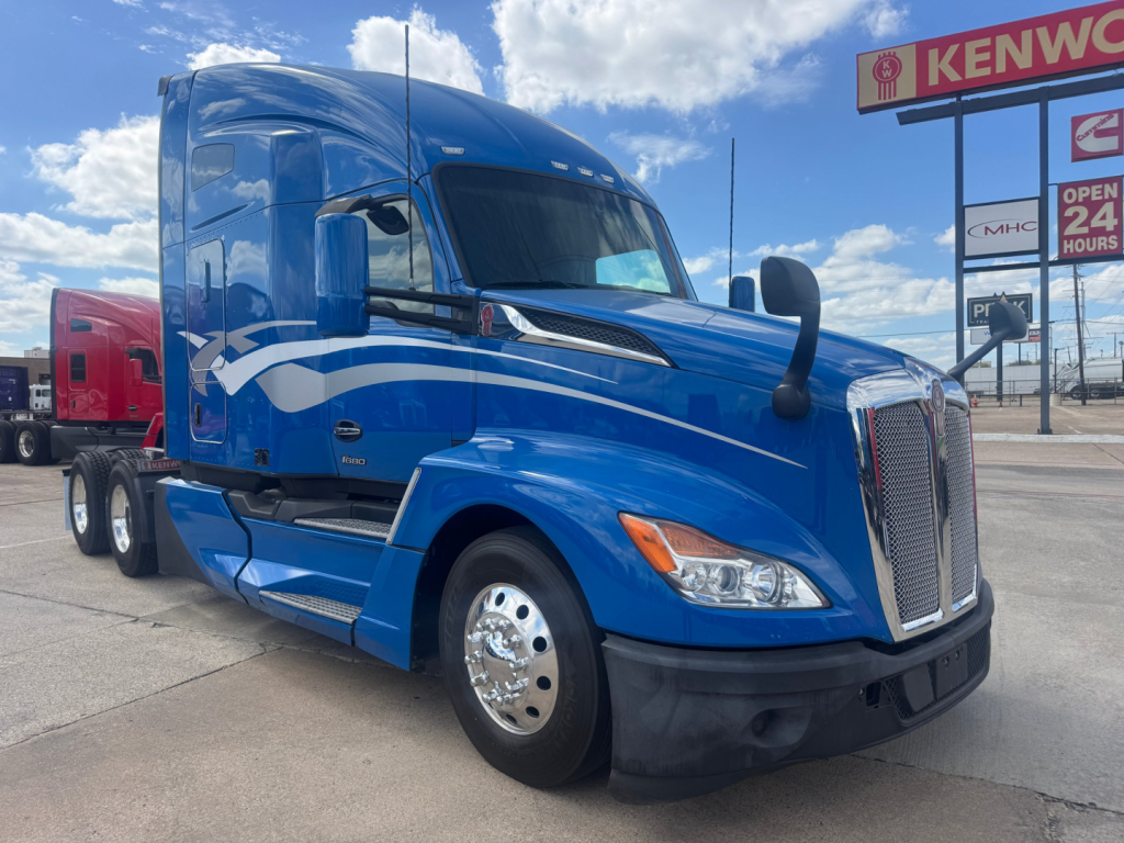 Kenworth T680 sleeper cab truck in blue with white graphics, front three-quarter view.