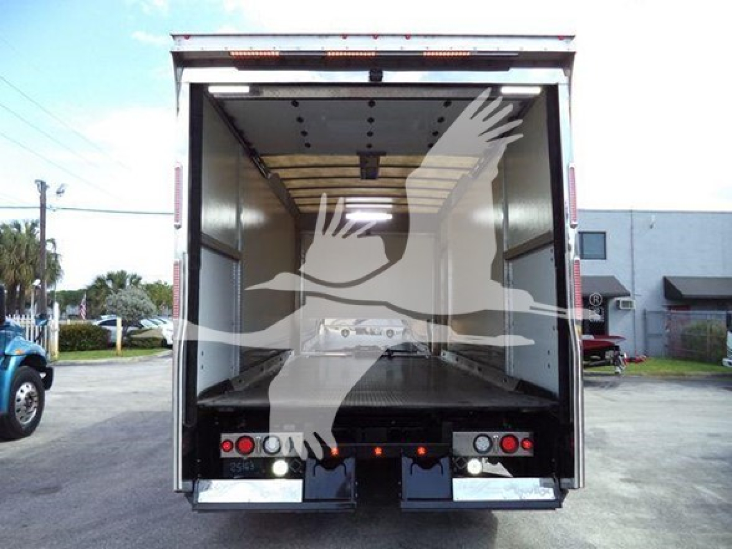 Truck rear view showing empty enclosed cargo area in a 2022 Mack MD6 rollback truck with open rear doors and reflective taillights.