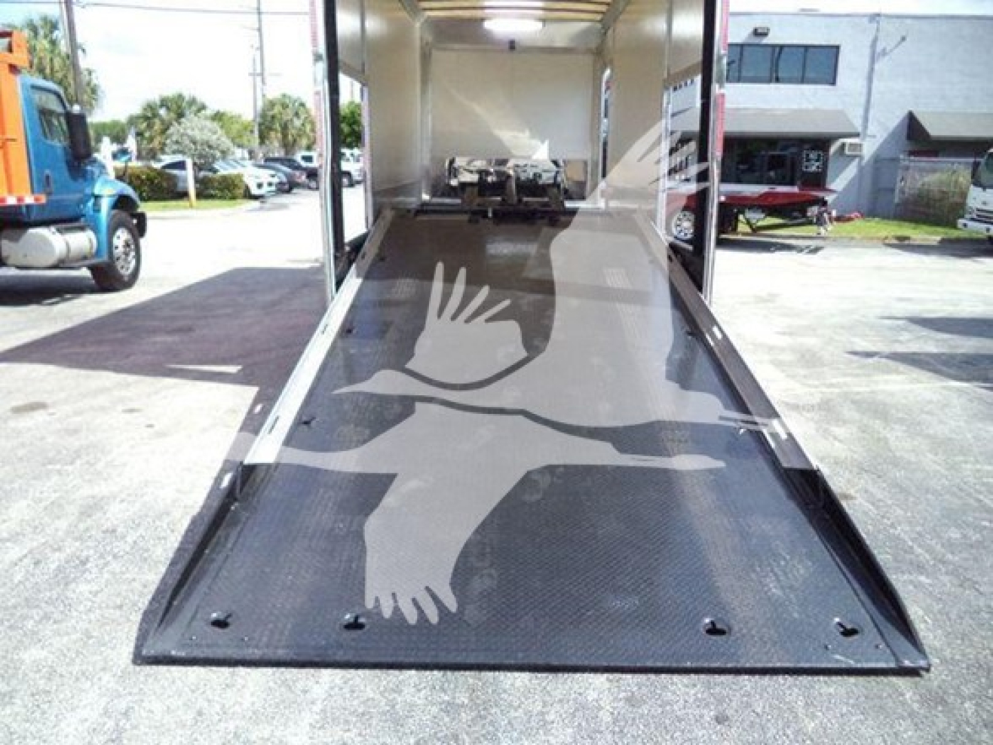 Truck bed with a rear ramps of a 2022 Mack MD6 rollback showing a long metallic ramp and loading area from rear perspective.