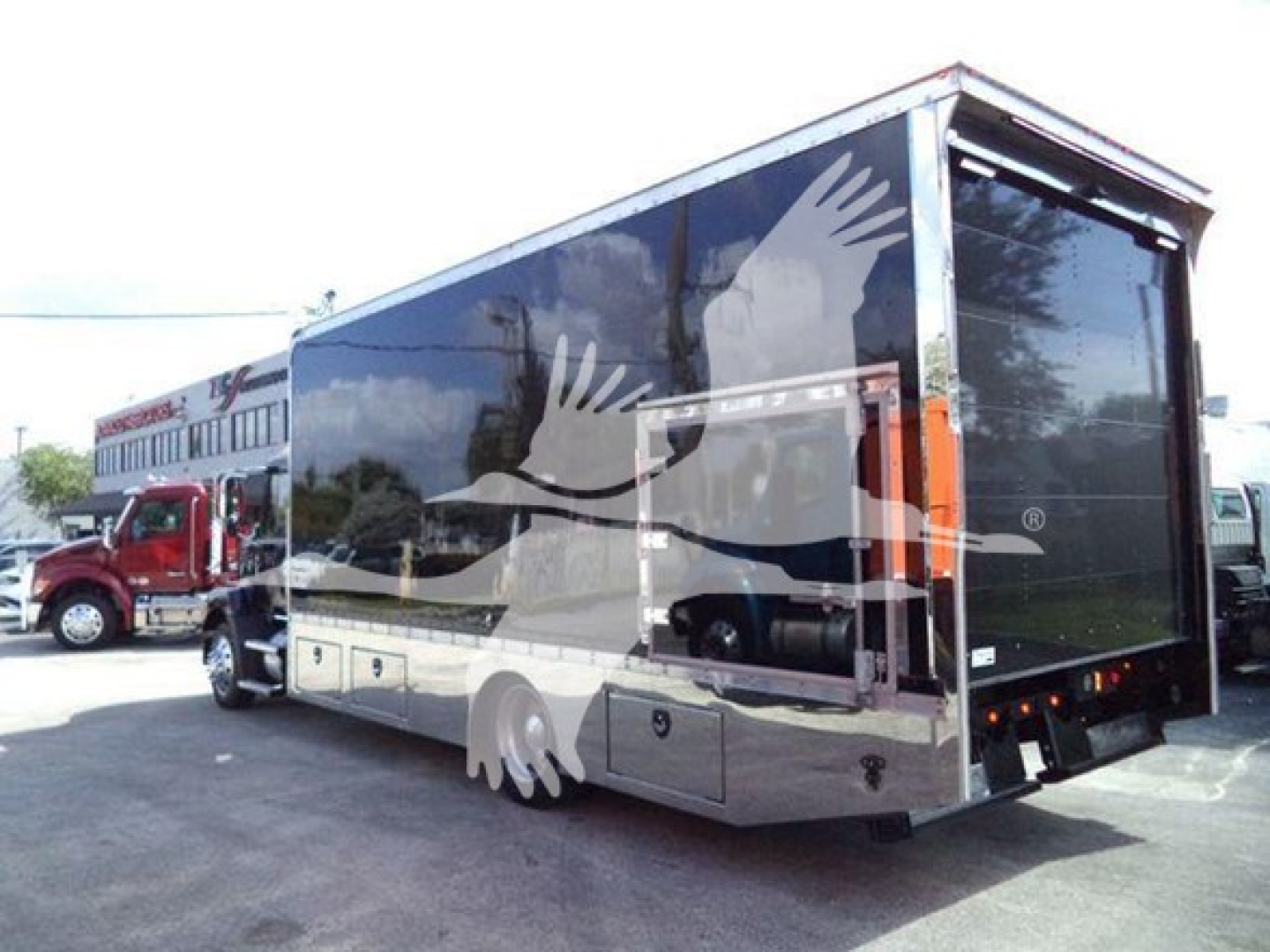 Truck bed area showing 2022 Mack MD6 rollback with enclosed cargo body and reflective surface.