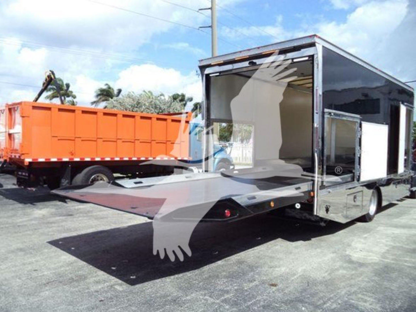 Truck bed with hydraulic rollback trailer showing folded ramp and cargo area; rear ramp extended; black/gray trailer with chrome accents.