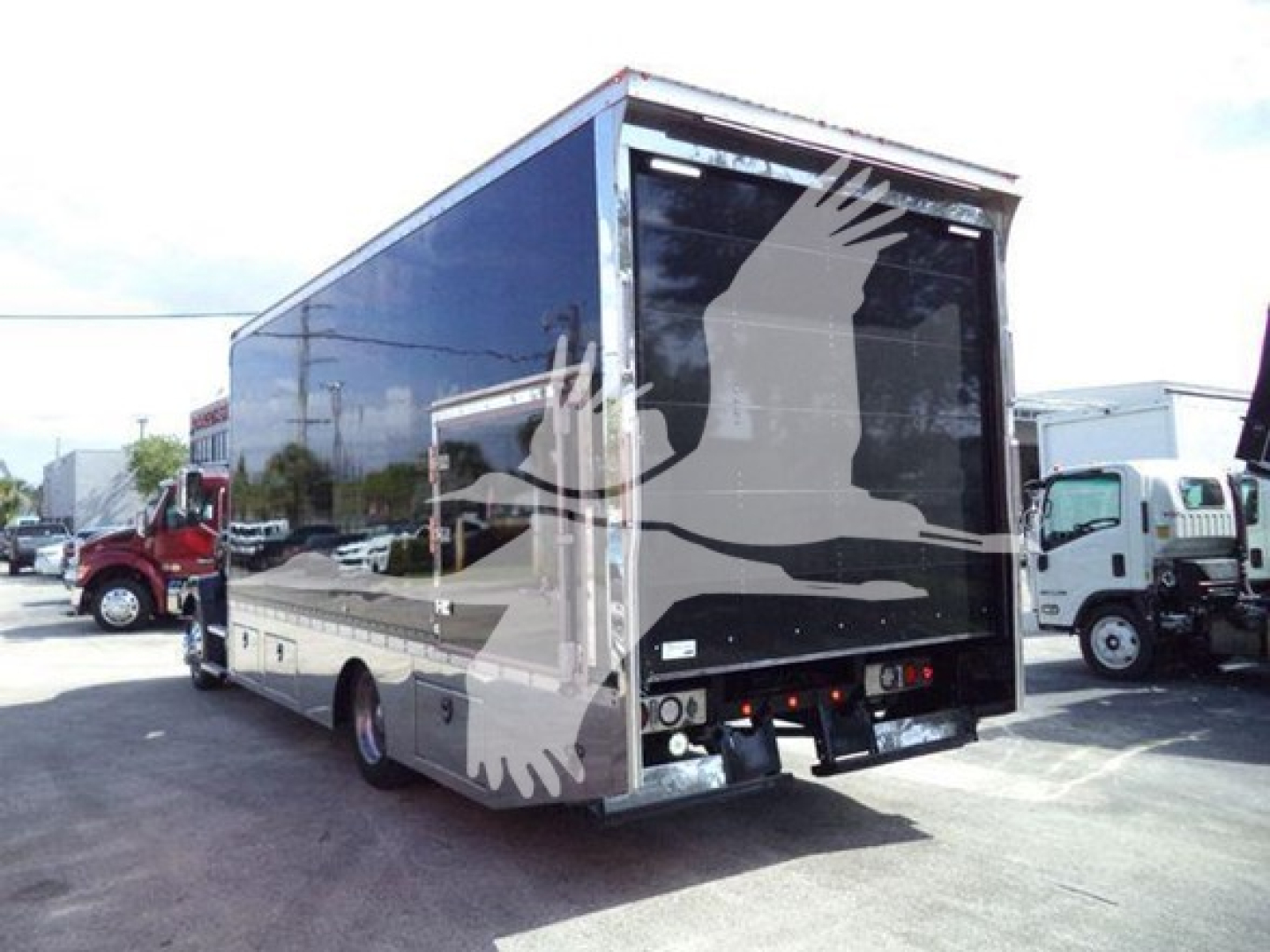 Back of a Mack MD6 rollback truck showing cargo area with black tailgate and rear lights.