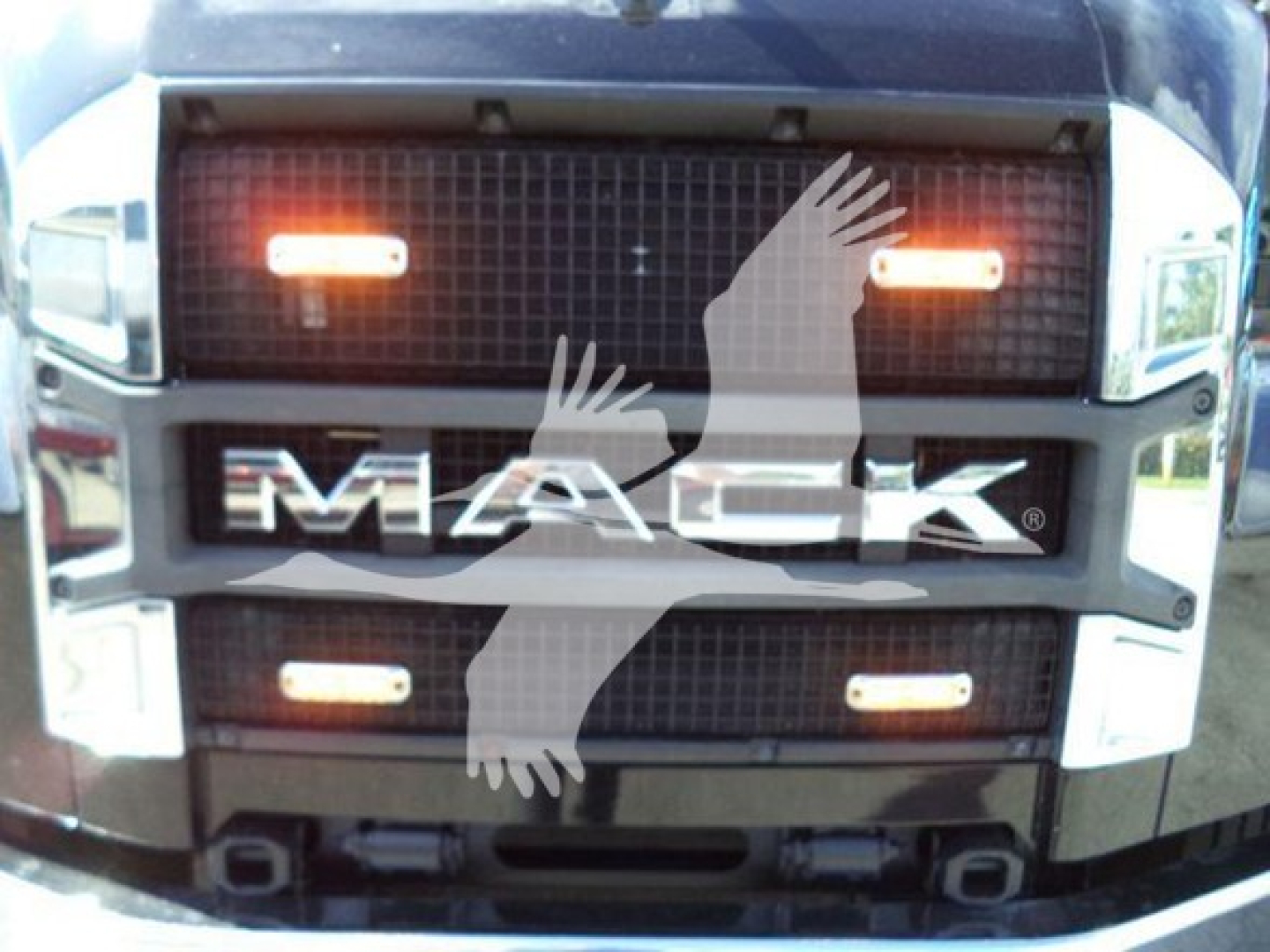 Mack MD6 grille front view showing illuminated amber clearance lights and MAC K emblem.