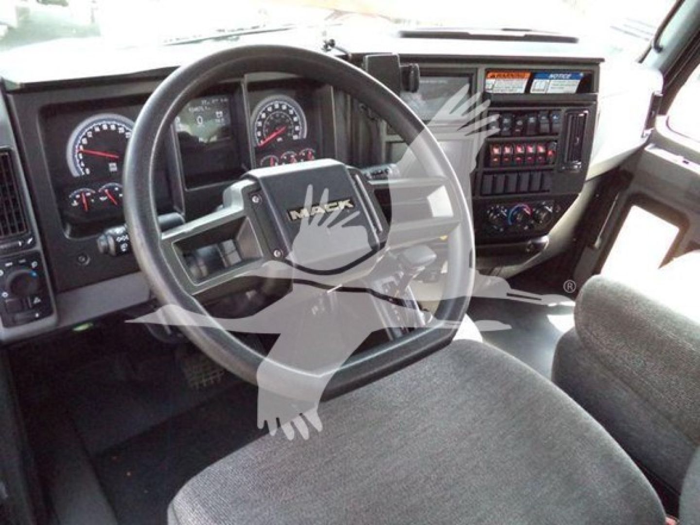 Dashboard and steering wheel interior of a Mack MD6 truck showing gauges, steering wheel with Mack logo, and control panel.