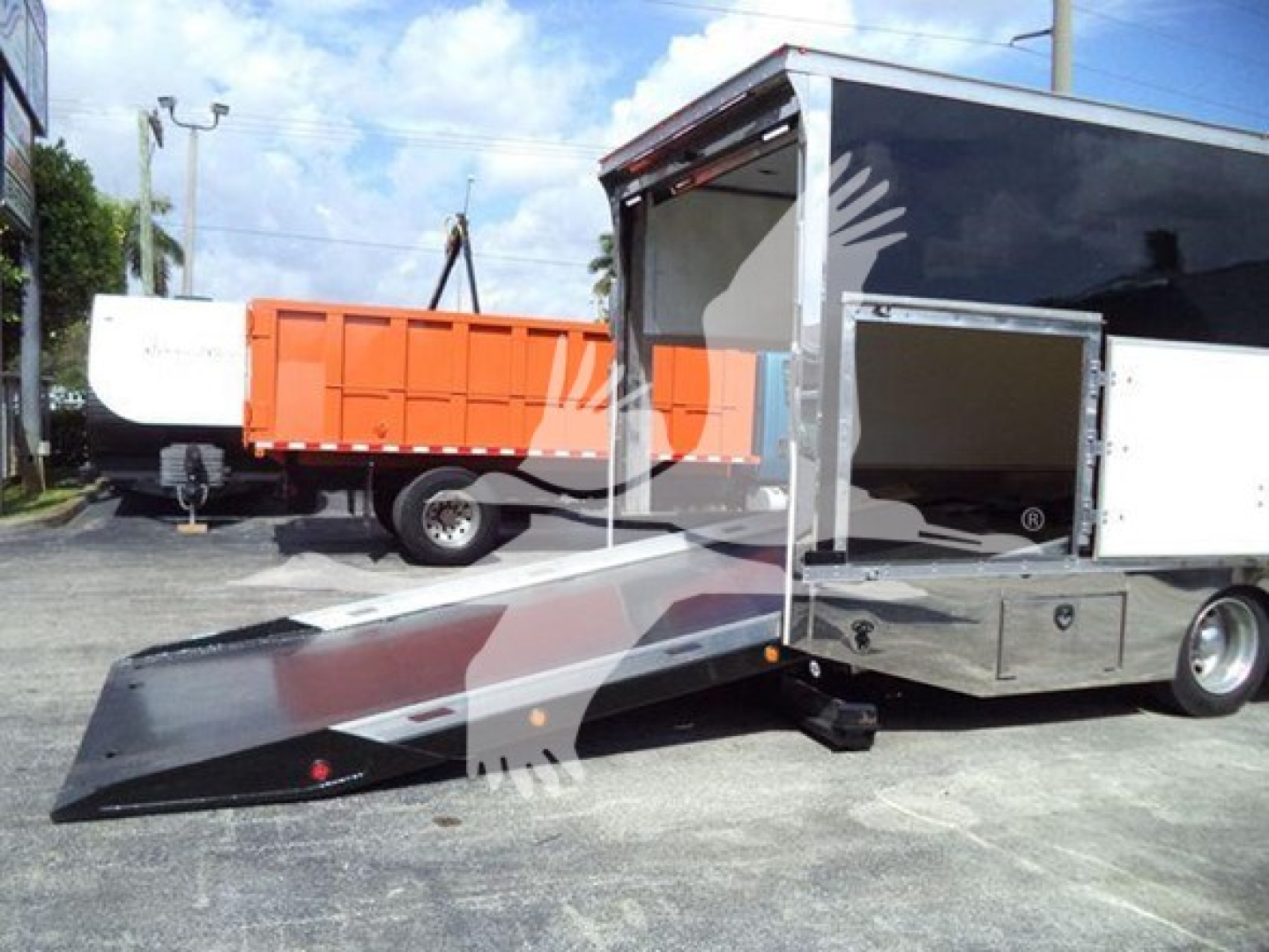 Mack MD6 rollback truck with ramp extended showing cargo bed and side open compartments.