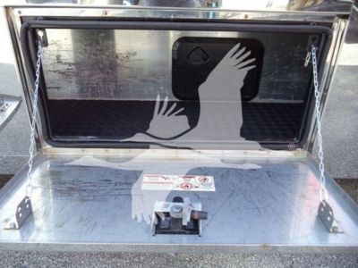 Trunk of 2022 Mack MD6 rollback showing rear storage area with metal deck, hinged tailgate, and warning labels.