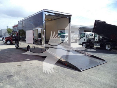 Truck trailer with a lowered ramp at the back, side door open showing interior. Exterior has a reflective finish.