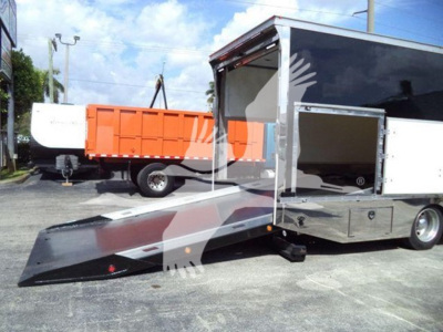 Mack MD6 rollback truck with ramp extended showing cargo bed and side open compartments.