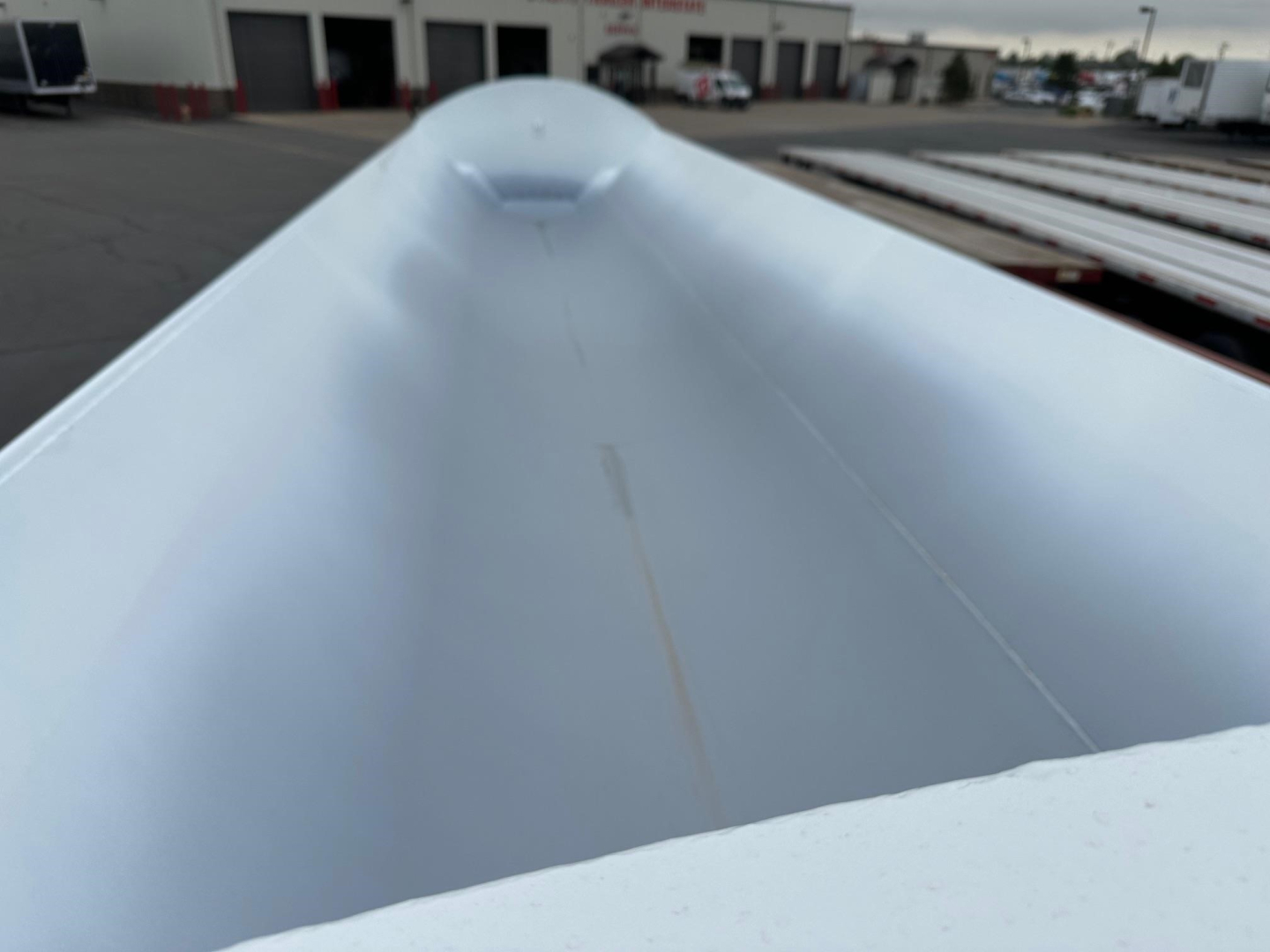 Triple-view of a 2026 Jet Side Dump trailer bed showing smooth metal interior and raised center ridge along the trailer.