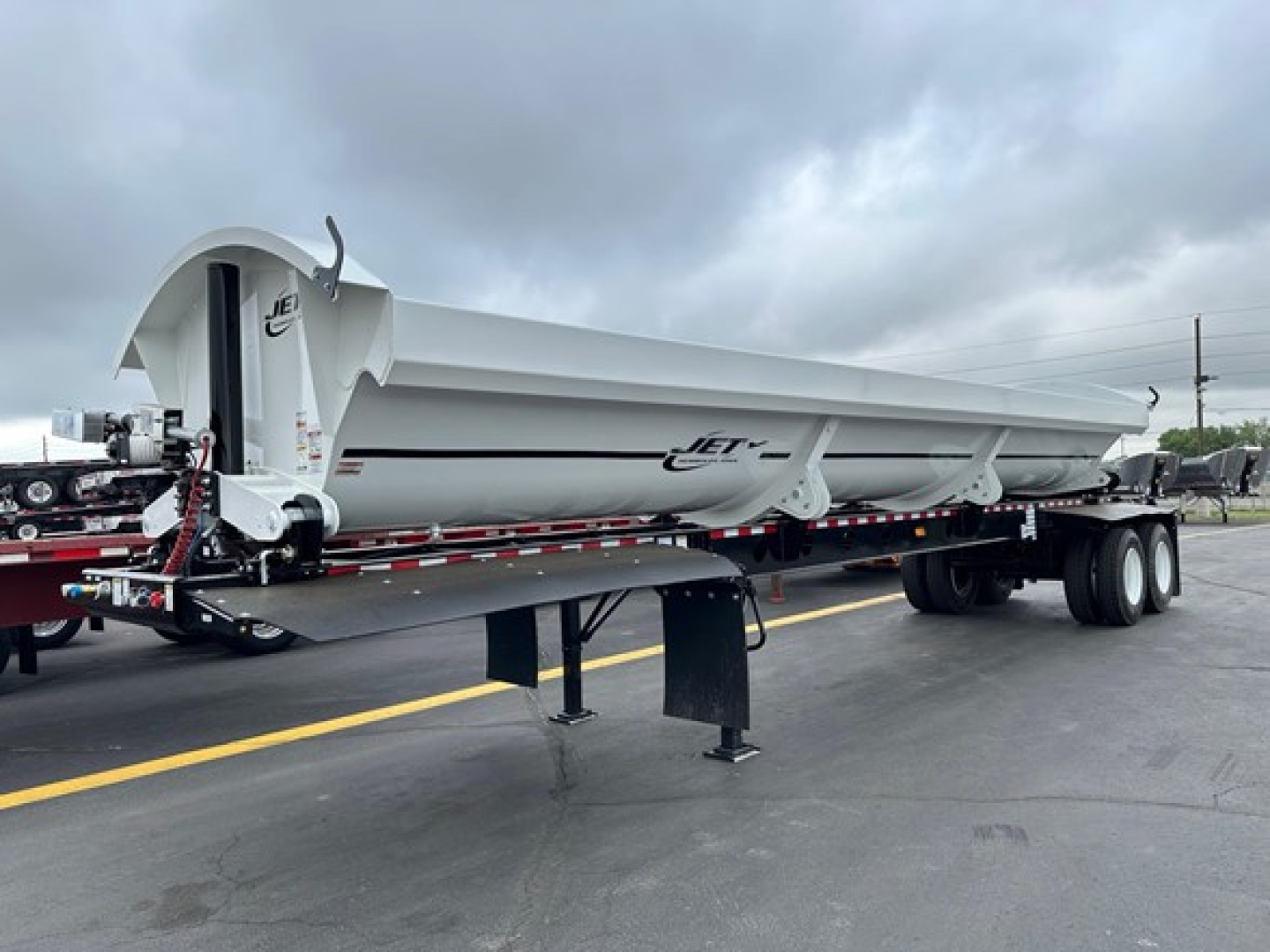 Jet side dump trailer showing long white dump body with Jet logo and triple-axle rear, on a lowboy trailer adjacent to a cab. VIN 150004407608 not visible on image.