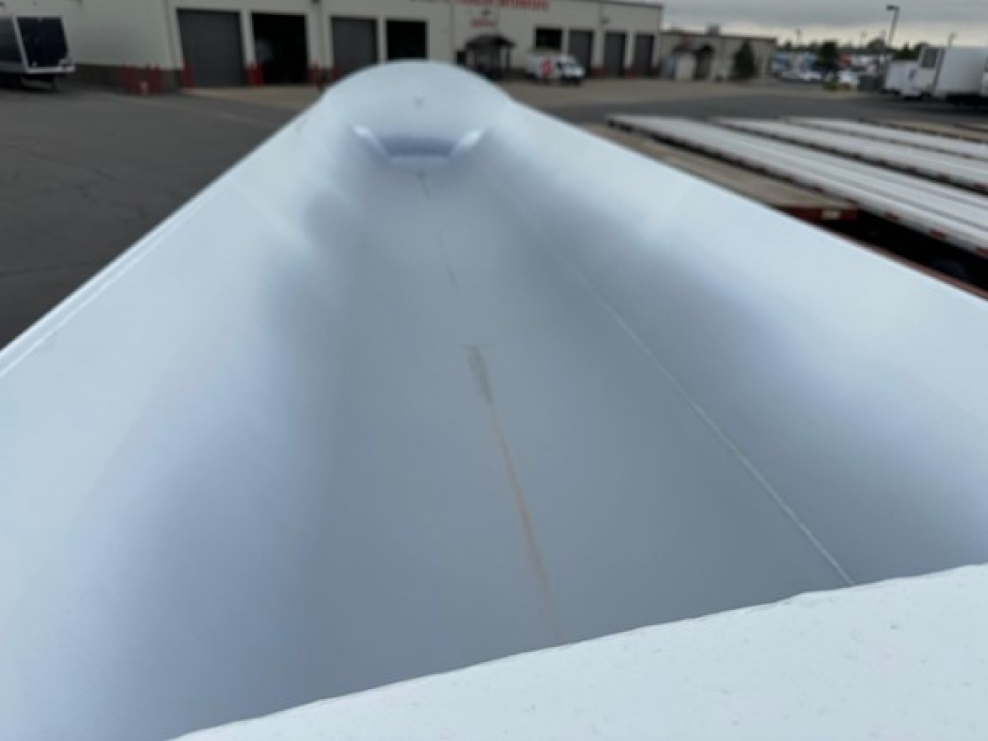 Trailer interior showing smooth light-gray metal surface with a long central seam and rounded peak at the front of a Jet Side Dump trailer.