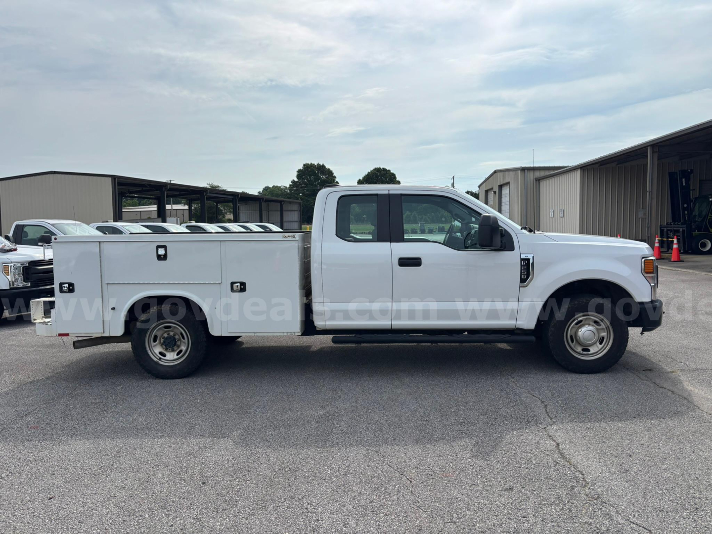 Ford F-250 service utility truck side view showing rear utility bed with compartments and dual rear wheels, white cab, generic dealership lot