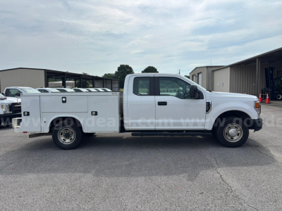 Ford F-250 service utility truck side view showing rear utility bed with compartments and dual rear wheels, white cab, generic dealership lot