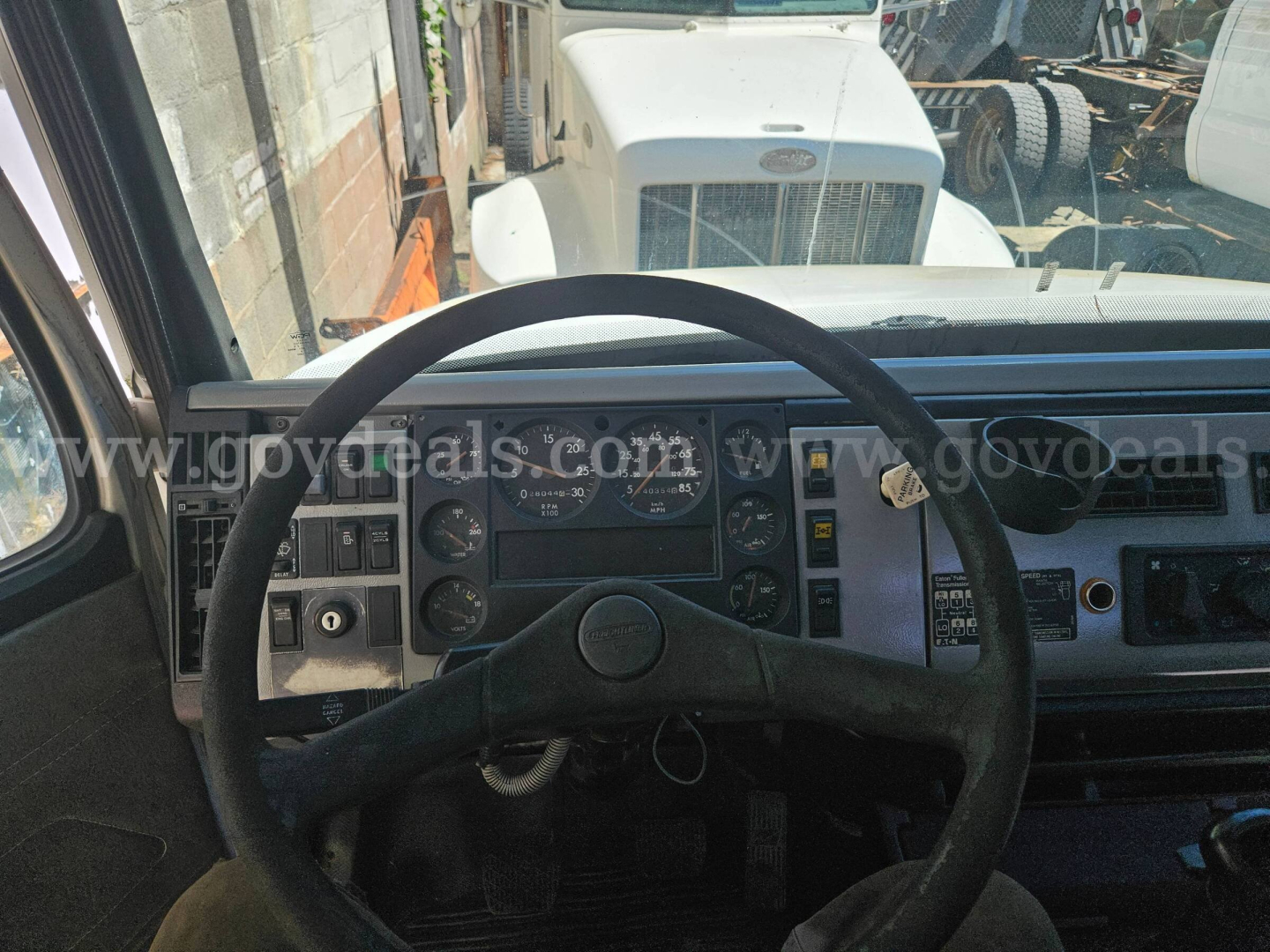 Cab and chassis interior: steering wheel and dashboard gauges visible, Freightliner truck dash in view.