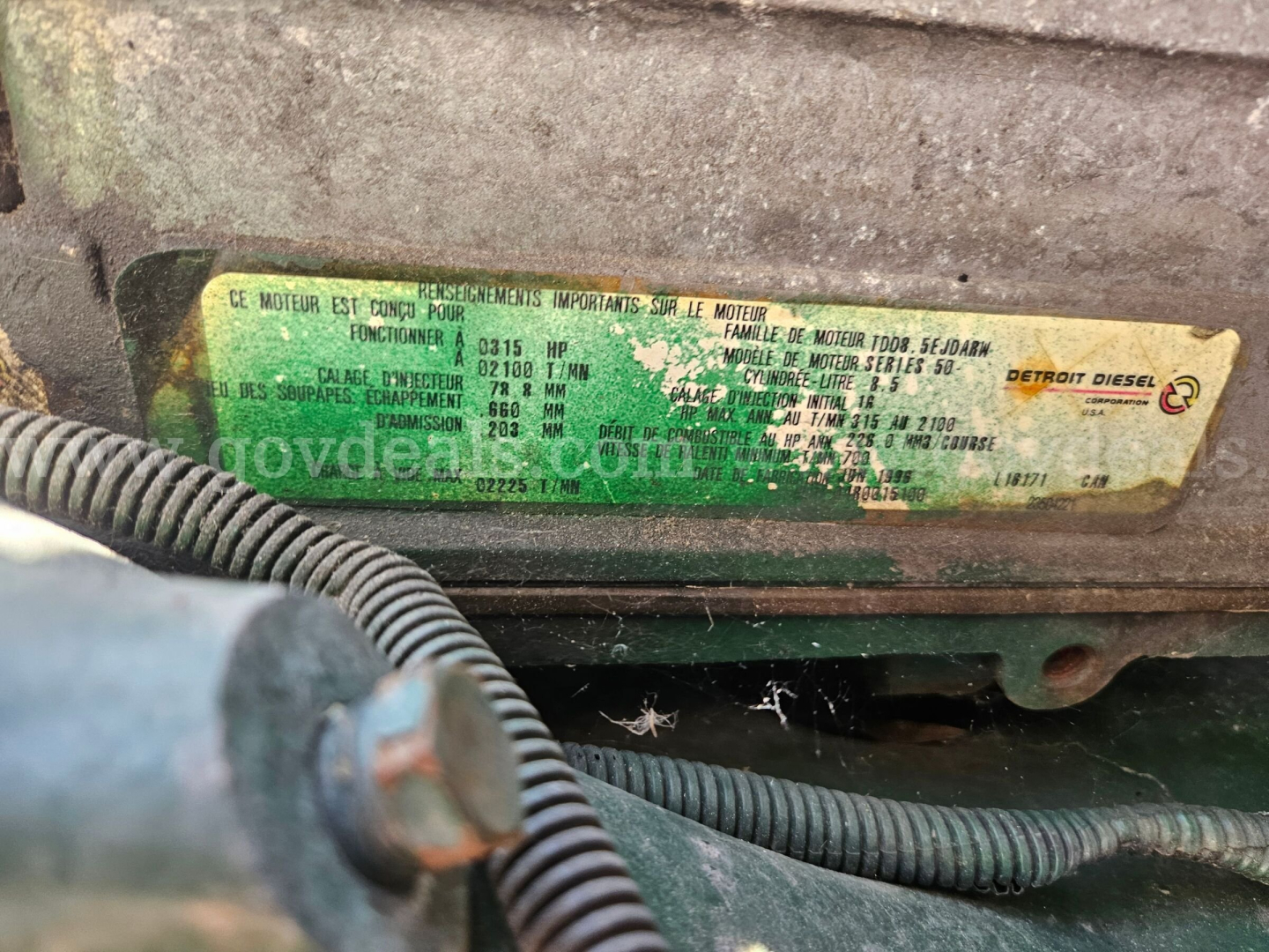 Label plate on Freightliner cab and chassis showing engine specs and identifiers; green/yellow sticker with text and numbers.