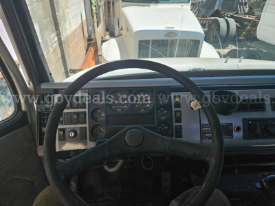 Cab and chassis interior: steering wheel and dashboard gauges visible, Freightliner truck dash in view.