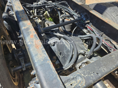 Truck chassis and engine bay of a Freightliner with visible hoses, belts, and wiring harnesses.
