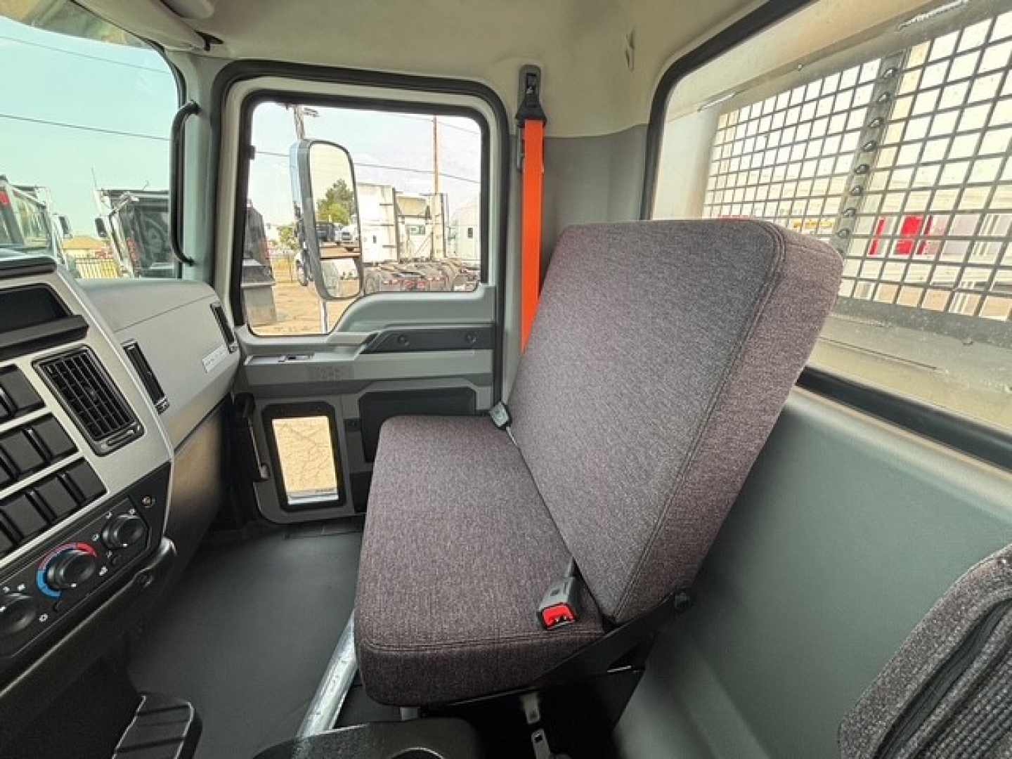Cab interior of a 2026 Mack MD7 truck showing driver seat and dashboard with control panel and window.