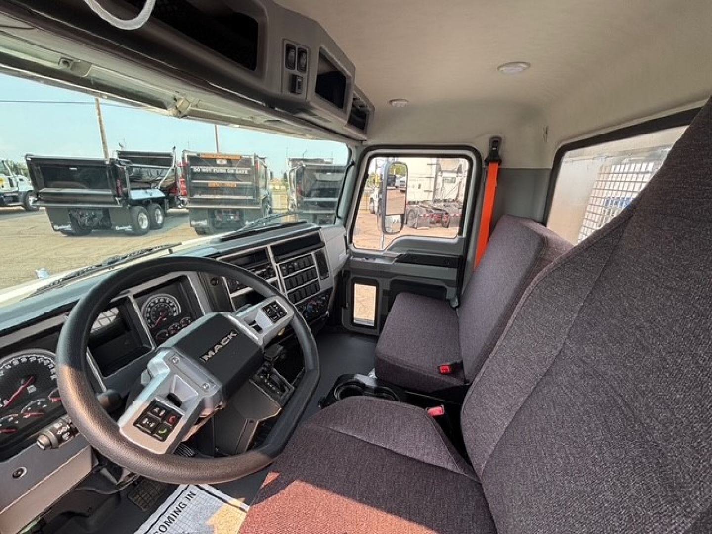 Cab interior of a 2026 Mack MD7 truck showing steering wheel, dashboard, and front seats from the driver side.