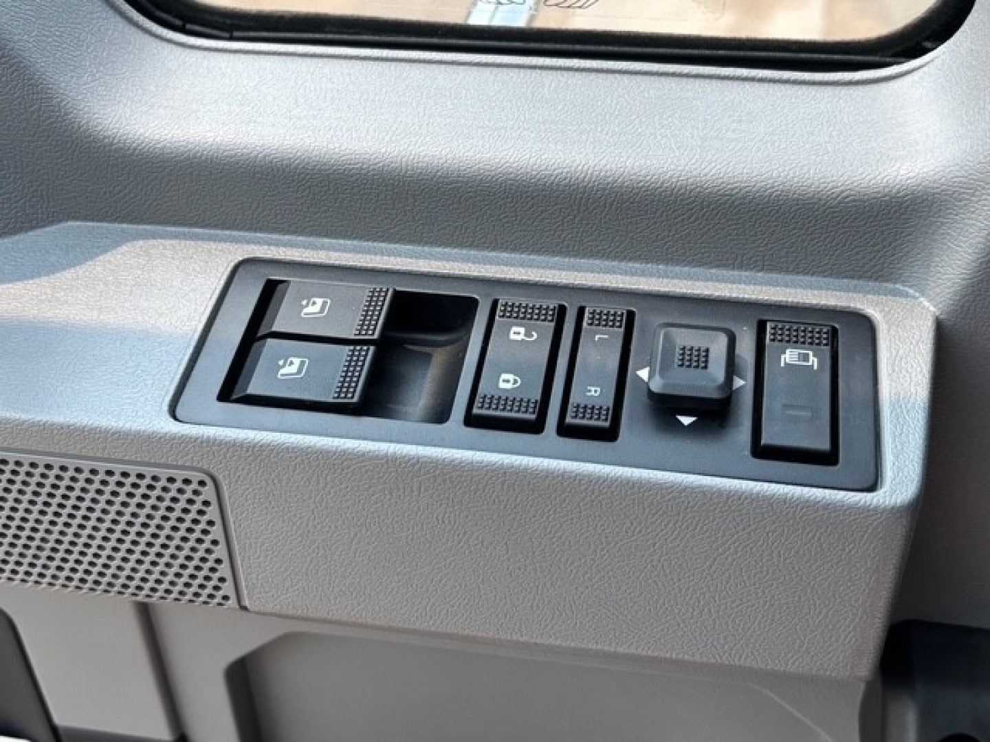 Truck interior door control panel with window controls and lock buttons. Adjacent text on controls includes icons for windows and locks.