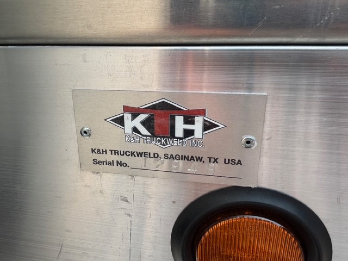 Plate and badge on the side of a Mack truck showing K&H Truckweld Inc. branding with Serial No. field visible.