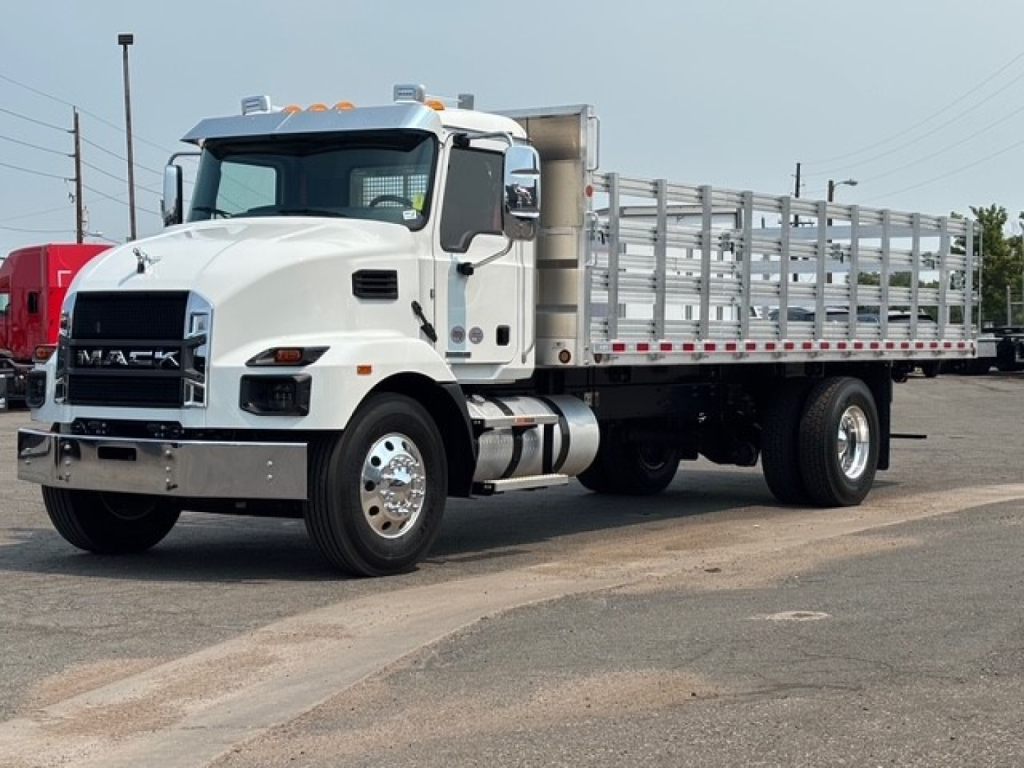 Truck cab and flatbed trailer with Mack branding on grille, white exterior, steel side rails, dual rear wheels visible