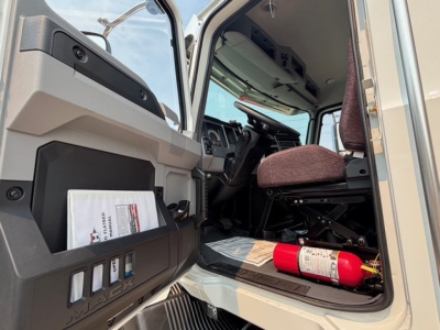 MD7 truck interior showing cab doorway with seat, steering wheel, and a fire extinguisher on the floor beside the door pocket.