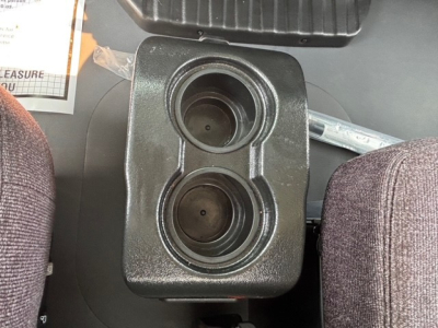 Front cup holder area with two circular cup holders in a central console of a Mack MD7 truck cab.
