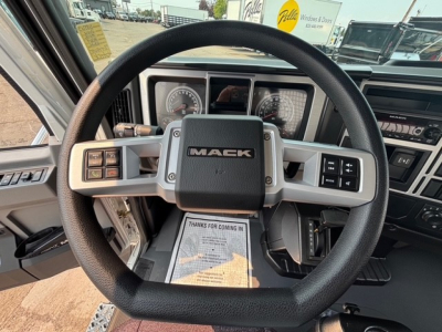 Mack MD7 steering wheel and dash showing center logo, instrument gauges, and control buttons in the cabin.
