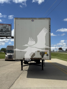 Rear view of a utility trailer 4000Dx, white with eagle logo, on a double-axle trailer with landing gear, stock number 4042-1, VIN 1UYVS2533EP898270.